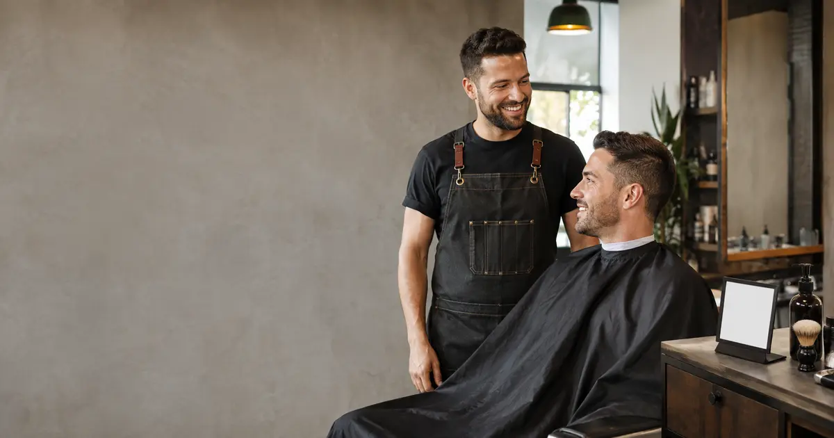 Barbier et client près d'une petite carte de réservation dans un salon moderne