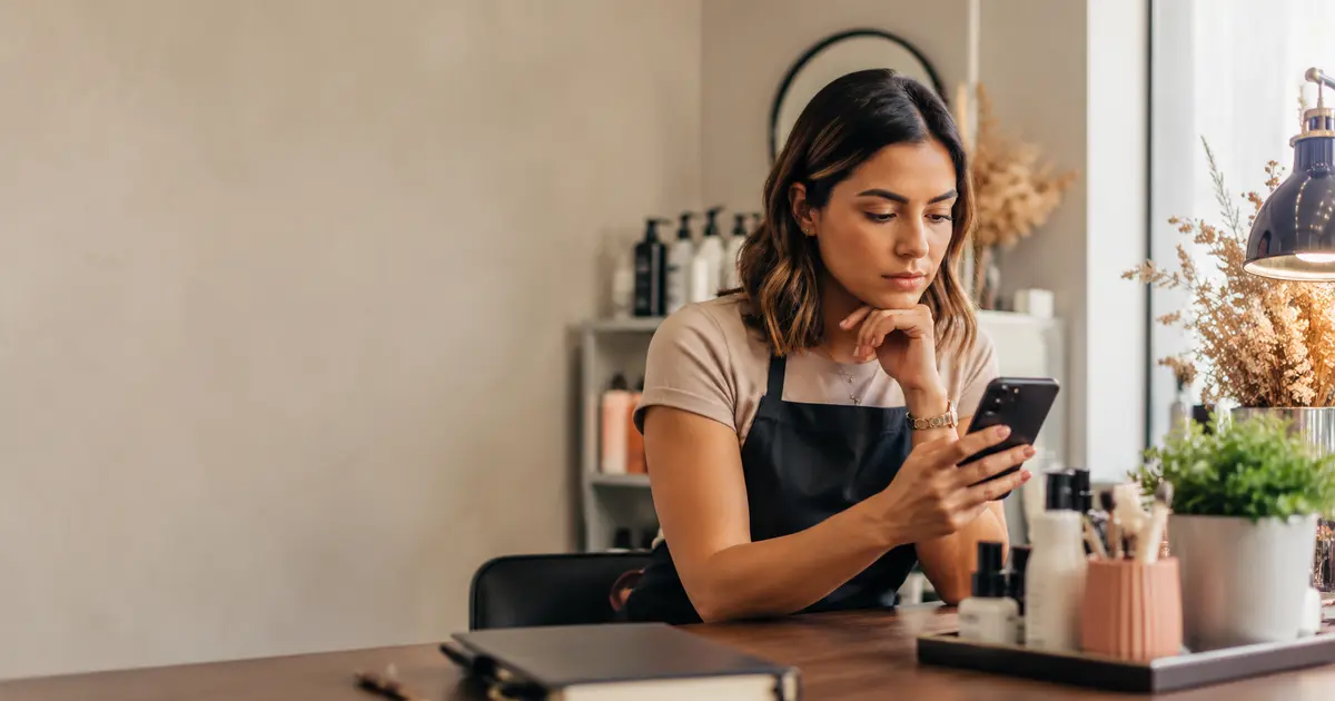 Beauty professional checking WhatsApp messages at a studio table